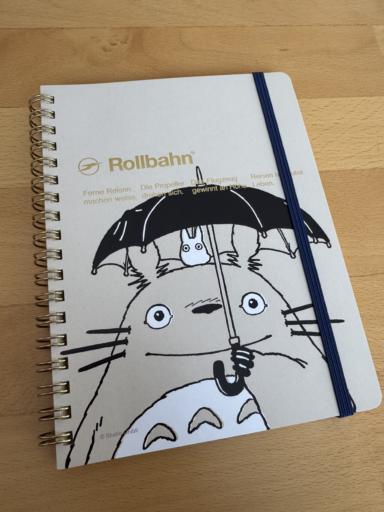 Cream colored Rollbahn notebook with a monochrome illustration of Totoro holding a black umbrella, with a white mini-Totoro on his head.
